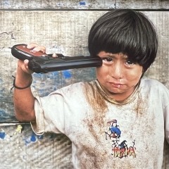 McCurry-Steve-Garcon-portant-un-pis-tolet-jouet-a-sa-tempe-Perou-2004